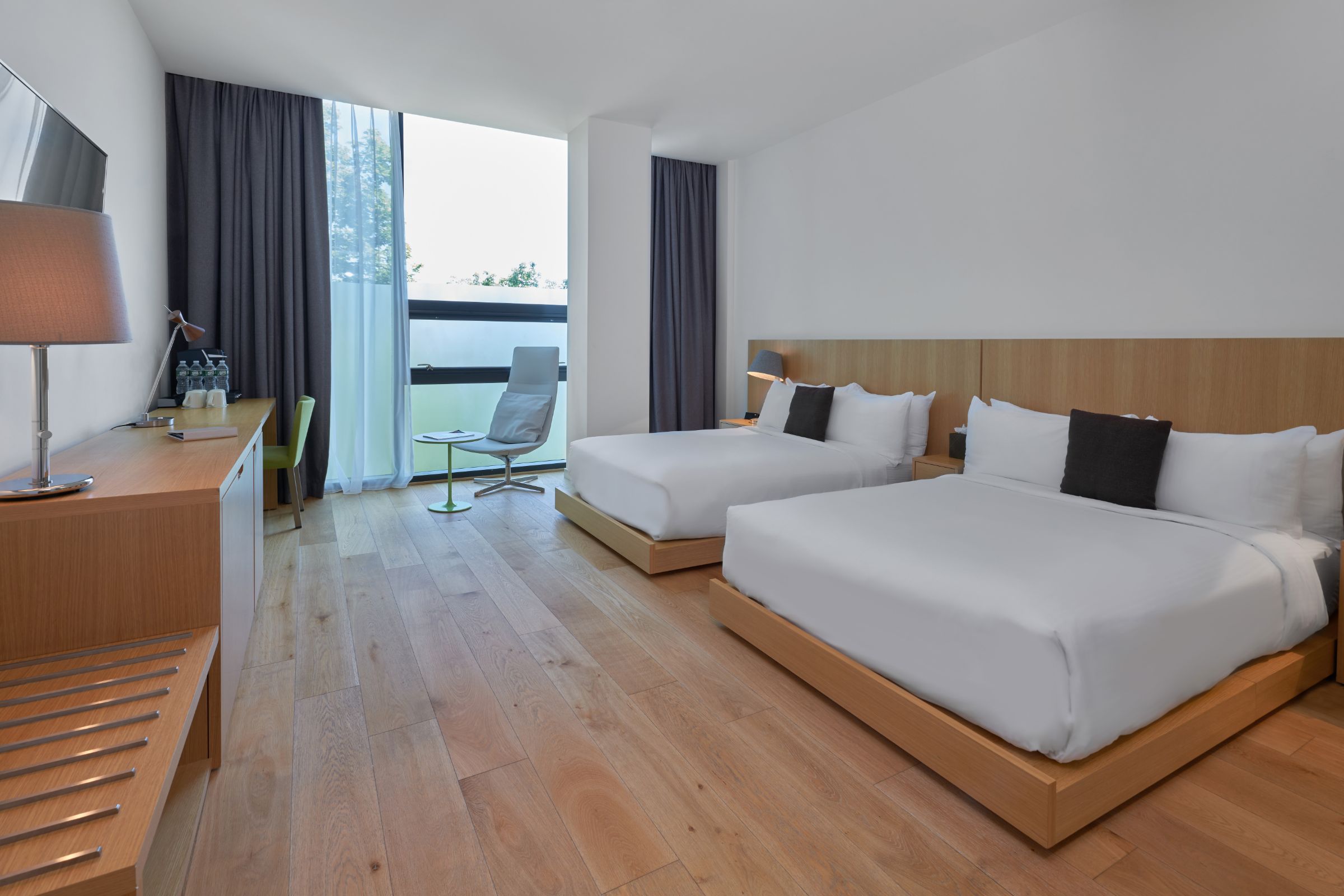 Double bedroom at Hotel SoJo designed with Eastern Asian aesthetic, minimal furtinure, floor to celing windows and wood floors.