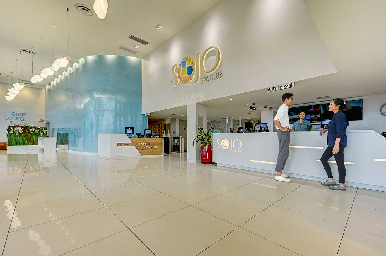 Two people smiling at each other while checking into SoJo Spa Club