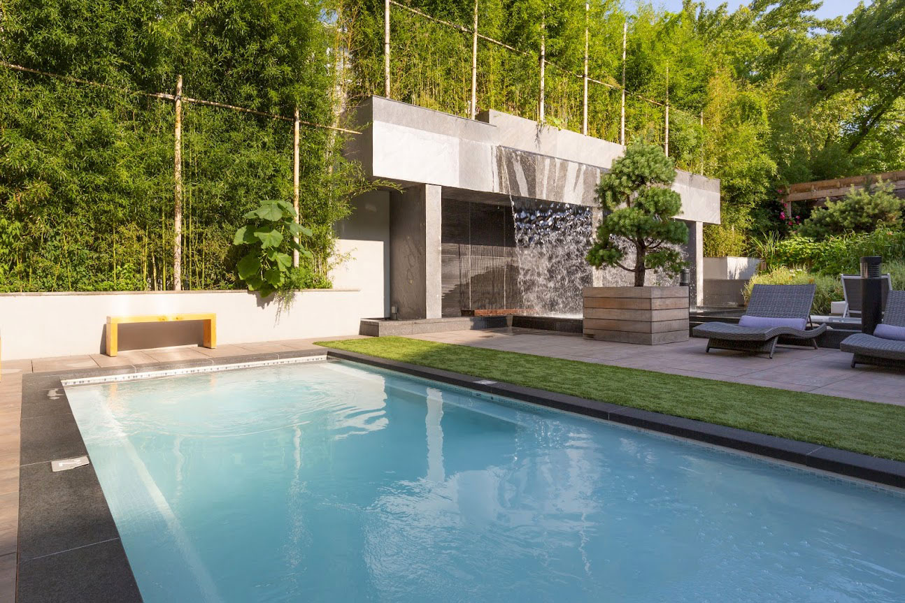 Heated silk bath surrounded by lush greenery, with a cold waterfall in the background. Lounge chairs on the deck under bright sunny day